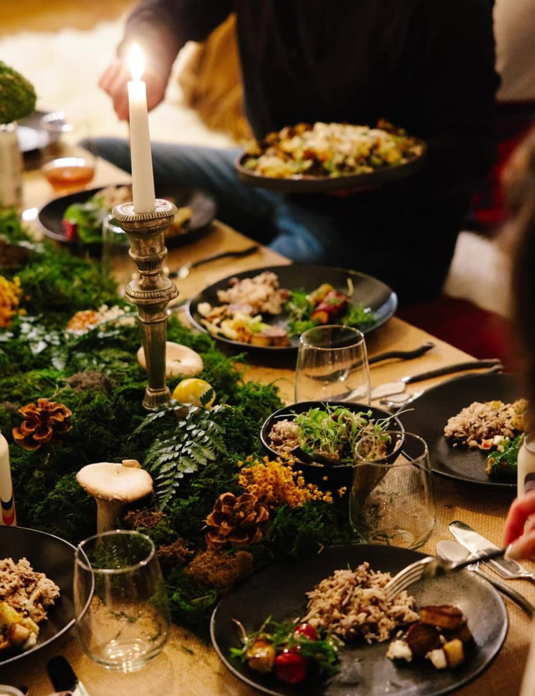 A table set with moss, candles, and shared plates